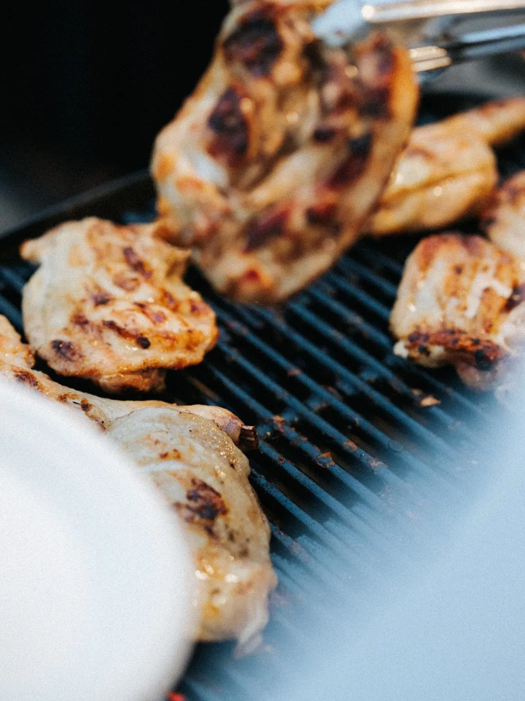 炭火のグリルで焼かれるあぶり焼きチキン。皿に取り分けられている。