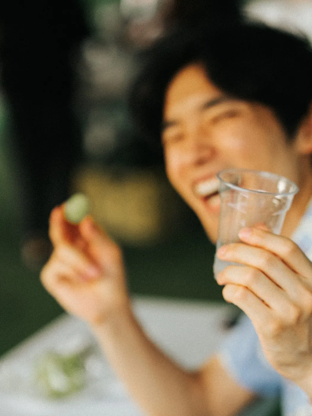 グラスを手に、声をあげて笑う来場者の男性。夕方のやわらかい光に包まれている。