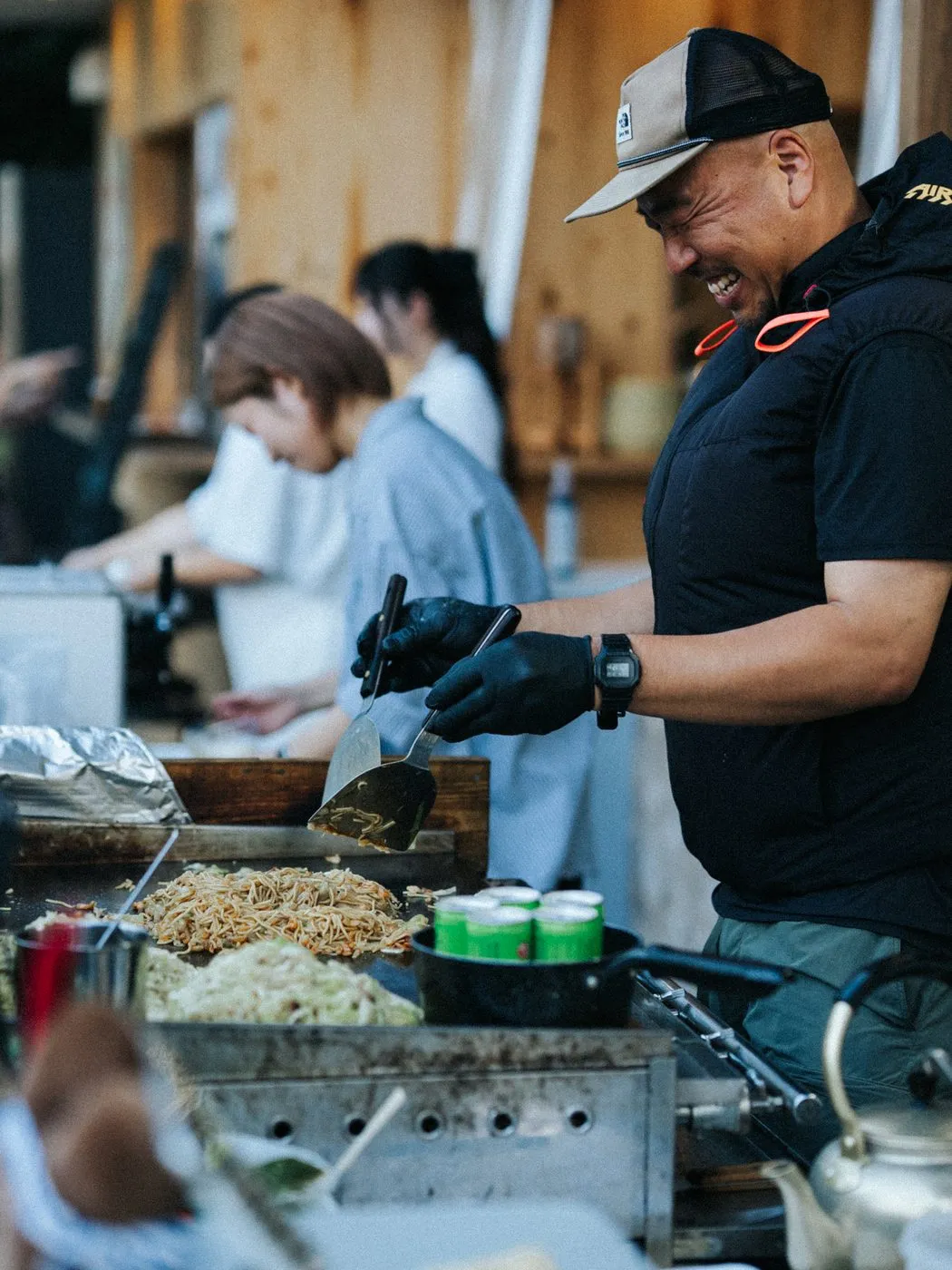 鉄板の前に立ち、焼きそばを調理する福山やきそば 村かずのスタッフ。笑顔で手を動かしている。